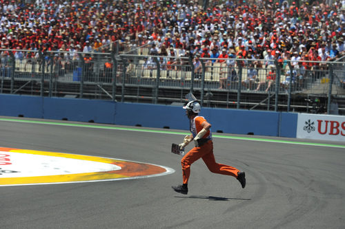 Un comisario recoge el trozo de alerón de Schumacher en Valencia