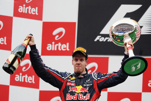 Vettel levanta en India su botella de champán y su trofeo