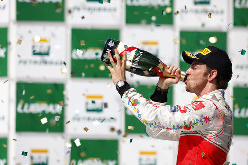 Jenson Button bebe champán en le podio de Brasil 2011