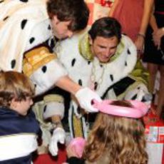 Fernando Alonso y Pedro de la Rosa bromean con una niña