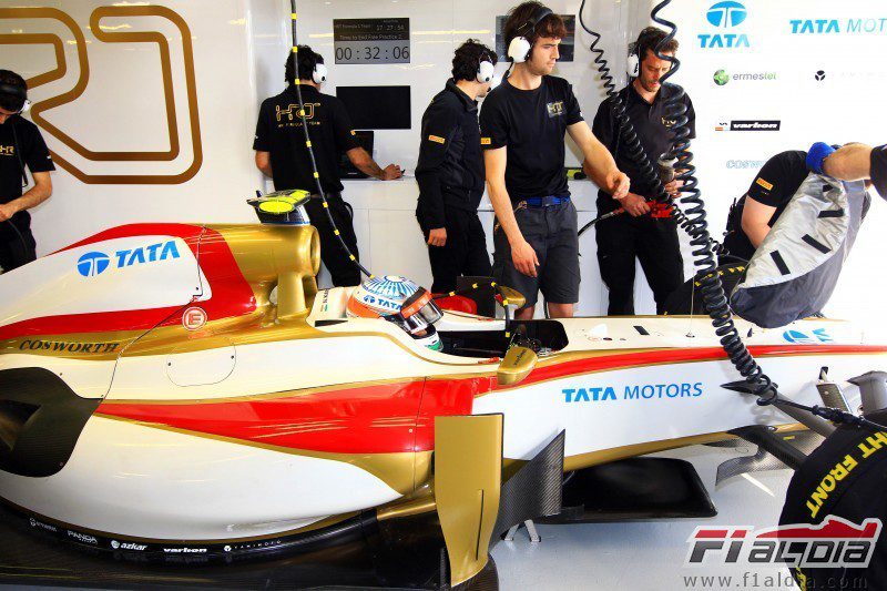 Los mecánicos de HRT siguen trabajando en el coche de Karthikeyan