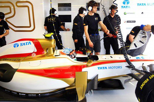 Los mecánicos de HRT siguen trabajando en el coche de Karthikeyan