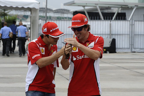 Fernando Alonso enseña algo en su móvil a Felipe Massa