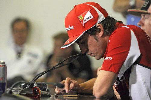Alonso juega con su iPhone durante la rueda de prensa de la FIA