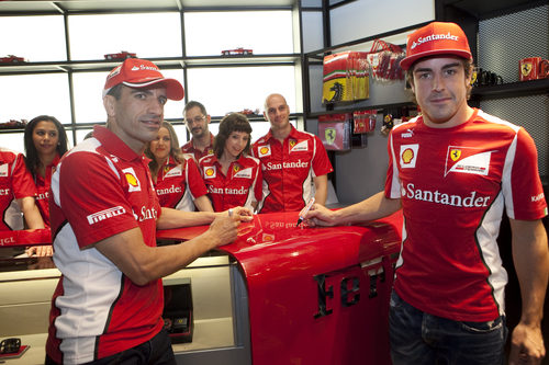 Marc Gené y Fernando Alonso firman sobre el mostrador de la Ferrari Store