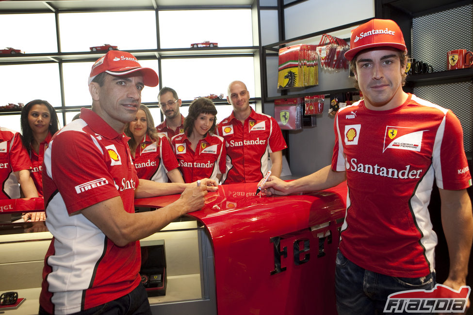 Marc Gené y Fernando Alonso firman sobre el mostrador de la Ferrari Store