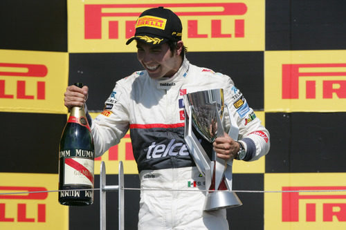 Sergio Pérez sostiene el trofeo y el champán en el podio