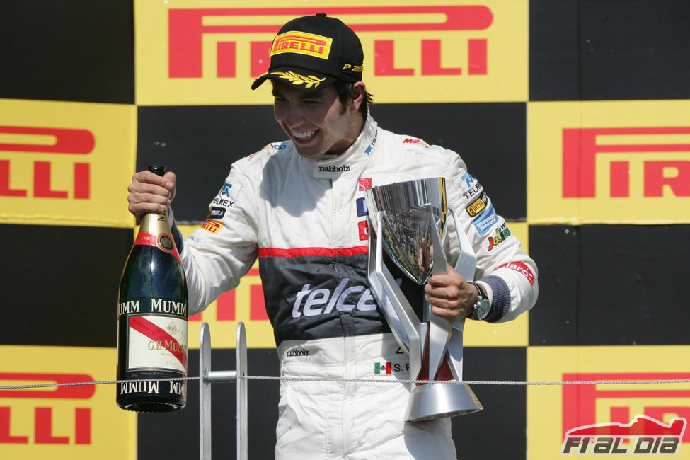 Sergio Pérez sostiene el trofeo y el champán en el podio