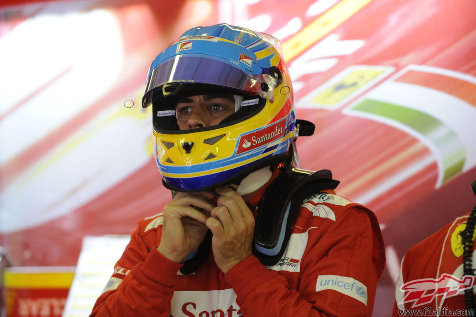 Fernando Alonso se ajusta el casco en el box de Ferrari