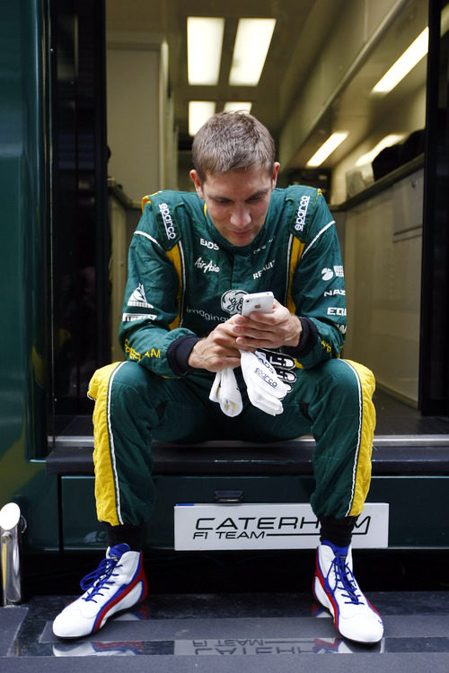 Vitaly Petrov juega con su iPhone con el mono puesto