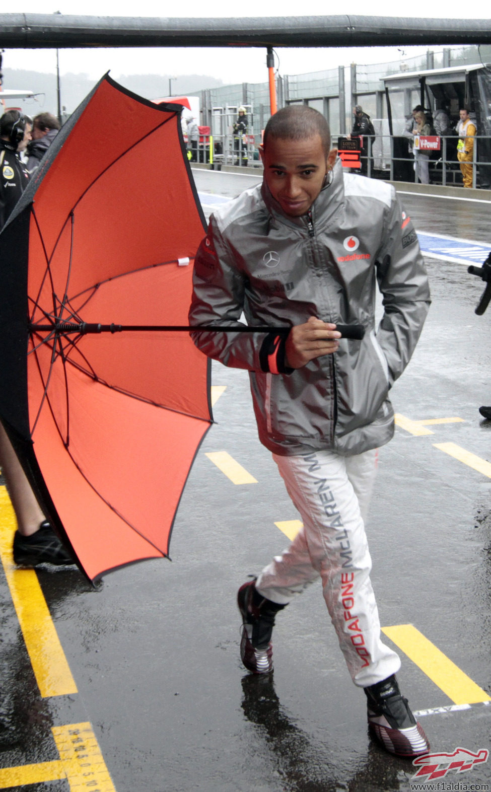 Lewis Hamilton pasea por el 'pit lane' de Spa con un paraguas