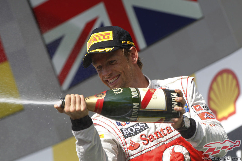 Jenson Button tira champán a su equipo desde el podio