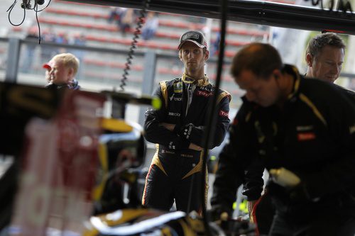 Romain Grosjean observa a sus mecánicos manipulando el Lotus E20