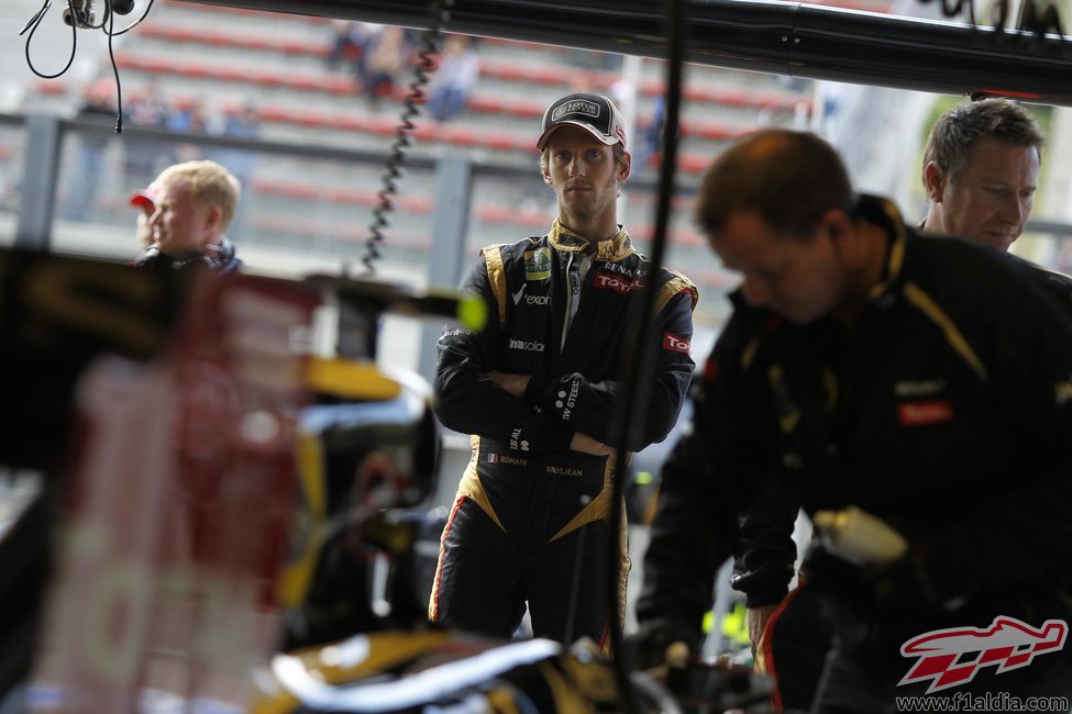 Romain Grosjean observa a sus mecánicos manipulando el Lotus E20