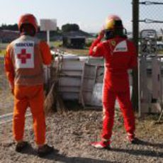 Un comisario y Fernando Alonso mirando la carrera desde las barreras