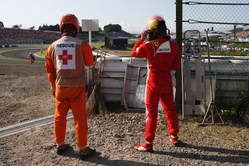 Un comisario y Fernando Alonso mirando la carrera desde las barreras