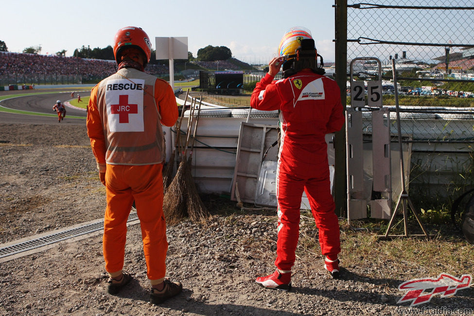 Un comisario y Fernando Alonso mirando la carrera desde las barreras