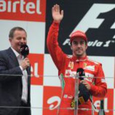 Fernando Alonso saluda desde el podio junto a Martin Brundle