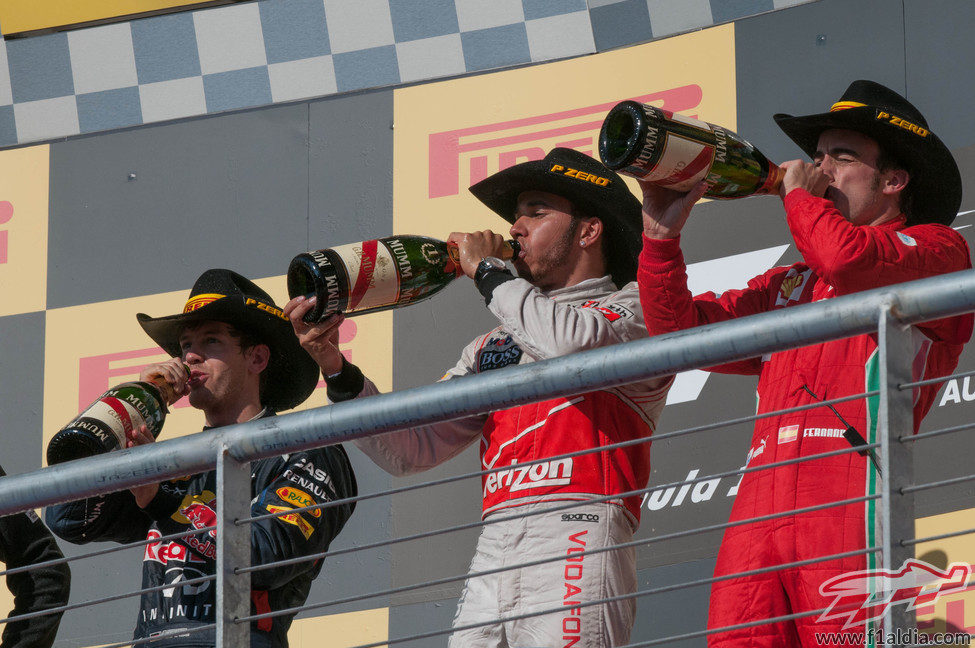 Los tres pilotos beben champán en el podio de Austin