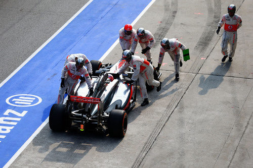 Los mecánicos de McLaren empujan el coche de Jenson Button