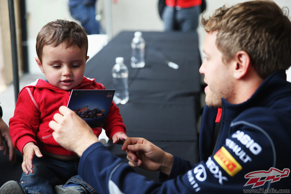 Sebastian Vettel le firma un autógrafo a un niño
