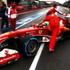 Los mecánicos de Ferrari entran el coche de Felipe Massa al box