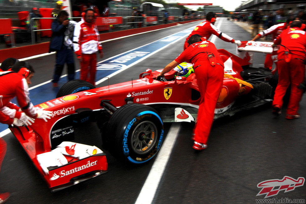 Los mecánicos de Ferrari entran el coche de Felipe Massa al box
