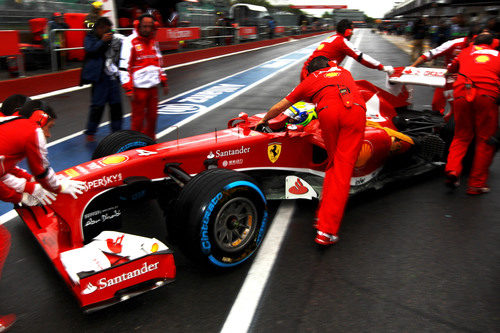 Los mecánicos de Ferrari entran el coche de Felipe Massa al box