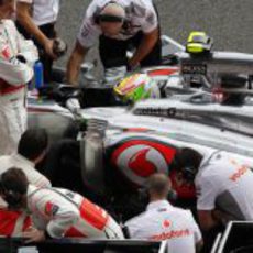 Los mecánicos de McLaren examinan el coche de Pérez en la parrilla