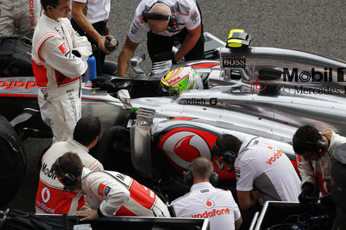 Los mecánicos de McLaren examinan el coche de Pérez en la parrilla