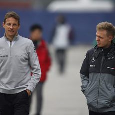 Kevin Magnussen y Jenson Button por el paddock