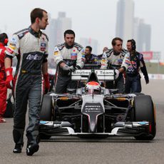 Adrian Sutil llevado por sus mecánicos hasta su posición de salida
