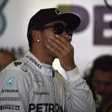 Lewis Hamilton observa algo en el box de Mercedes