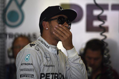 Lewis Hamilton observa algo en el box de Mercedes