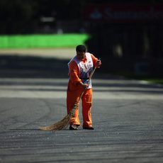 Un comisario quita los restos de suciedad de la pista