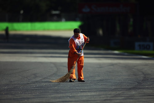 Un comisario quita los restos de suciedad de la pista