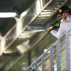 Lewis Hamilton lanza champán desde el podio