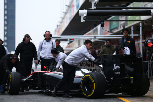 Los mecánicos llevan a Jenson Button de vuelta al box