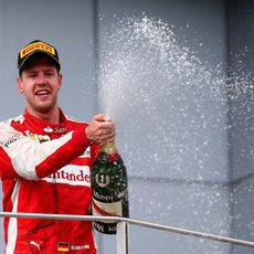 Sebastian Vettel moja con el champán a su equipo desde el podio