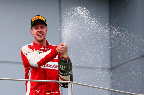 Sebastian Vettel moja con el champán a su equipo desde el podio