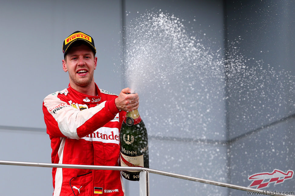 Sebastian Vettel moja con el champán a su equipo desde el podio