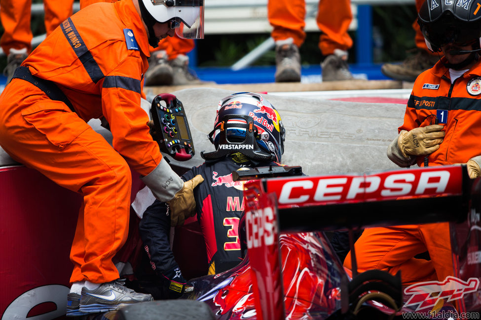Los comisarios ayudan a salir del coche a Max Verstappen