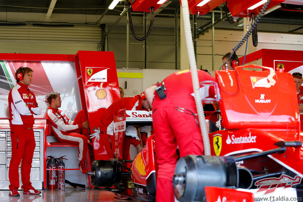 Sebastian Vettel en el box de Ferrari mientras el equipo trabaja