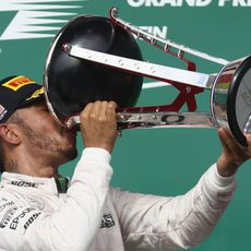 Lewis Hamilton bebe del trofeo ganador