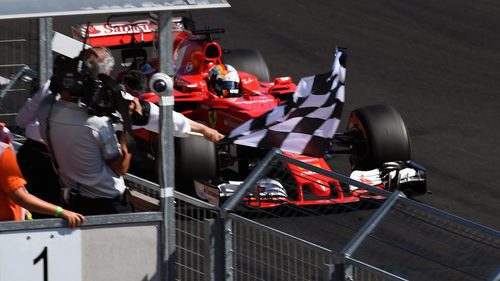 Vettel pasando junto a la bandera de cuadros