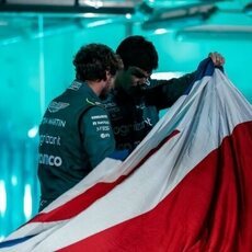 Los pilotos de Aston Martin mirando bajo la bandera