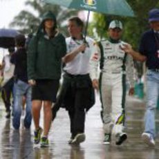 Heikki Kovalainen pasea por el lluvioso 'paddock' de Sepang