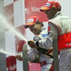 Timo Glock y Lewis Hamilton riegan a sus equipos con champán