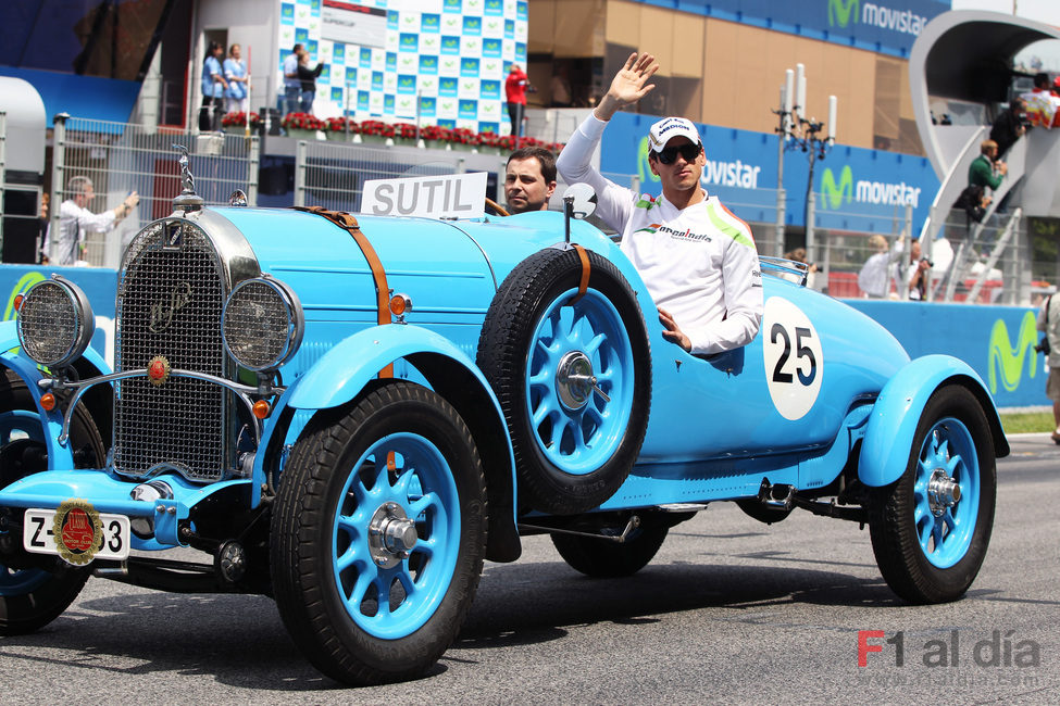 Adrian Sutil saluda al público español sobre un coche clásico