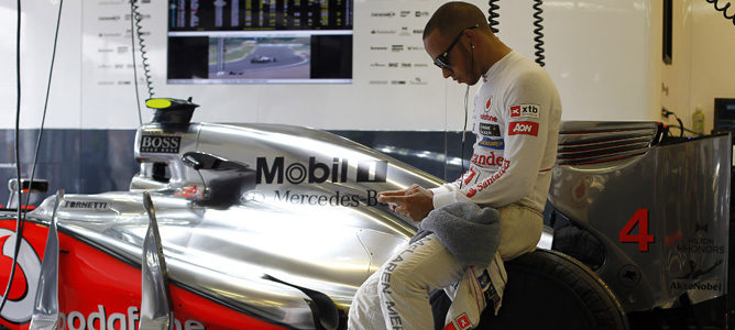 Lewis Hamilton junto a su monoplaza en el box